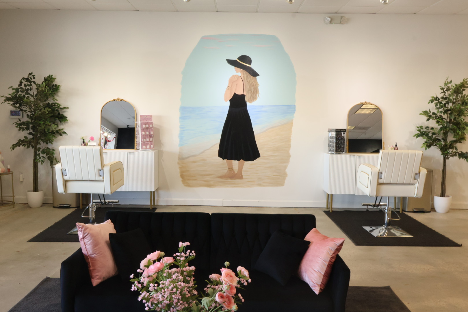 The two ear piercing stations at Evermore in Foley, AL — cream salon chairs, gold-framed mirrors and a hand-painted beach mural